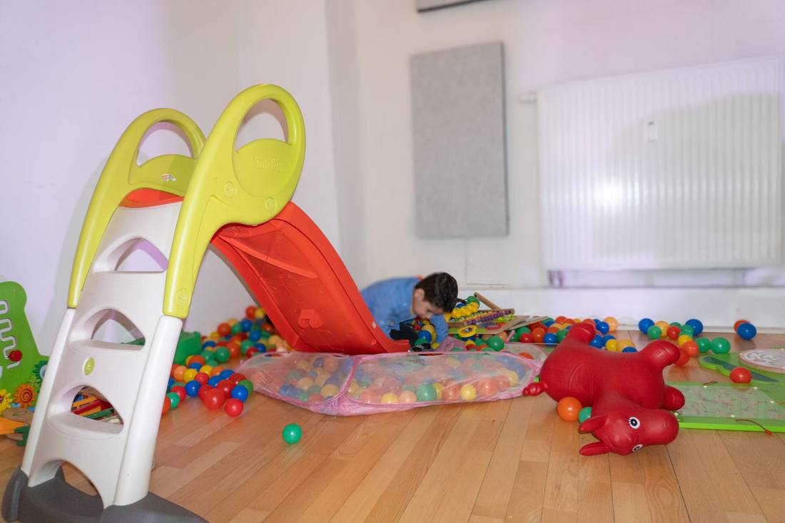 Kind spielt im Bällebad neben der Rutsche im Kinderspielbereich des Partyraums